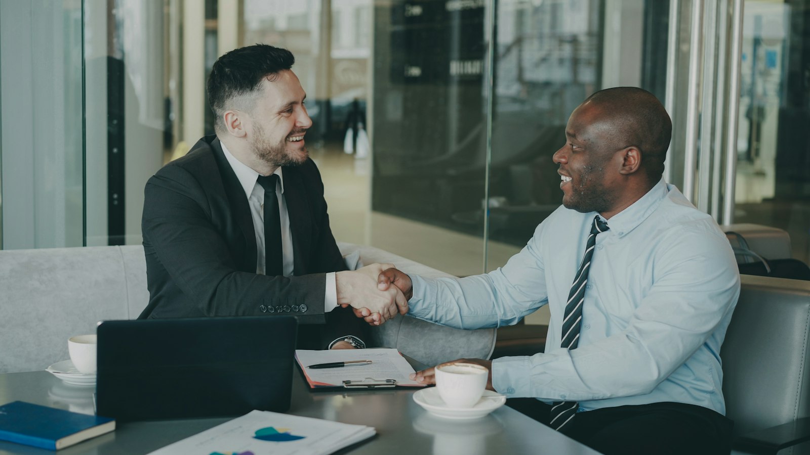 Two people shaking hands across a table