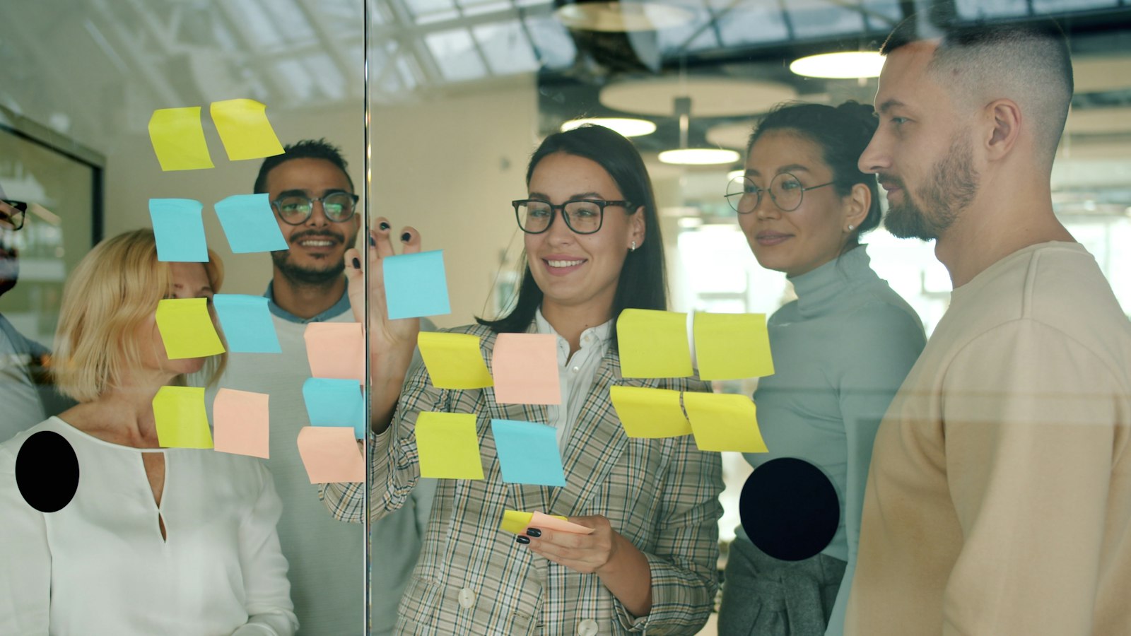 Team planning strategy with sticky notes on glass